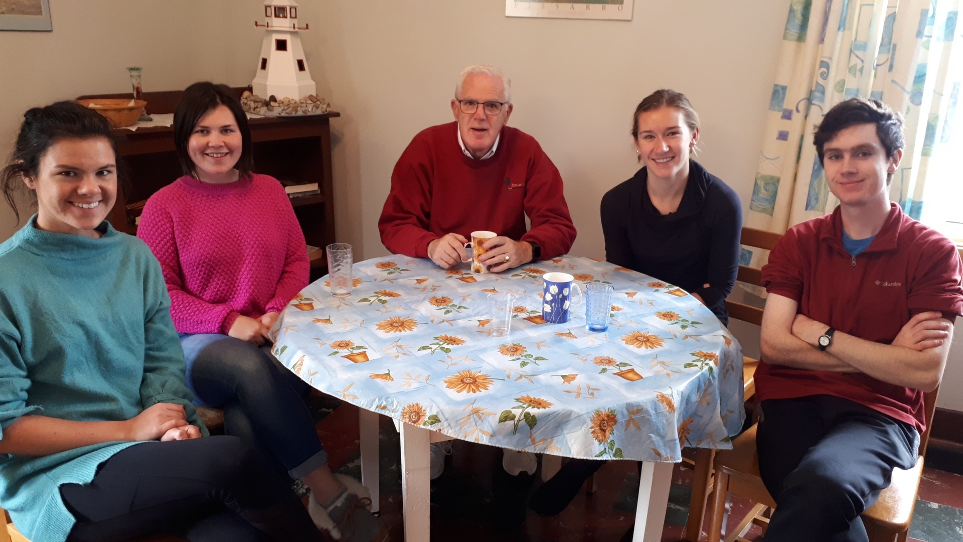 Five people sitting at a table and smiling
