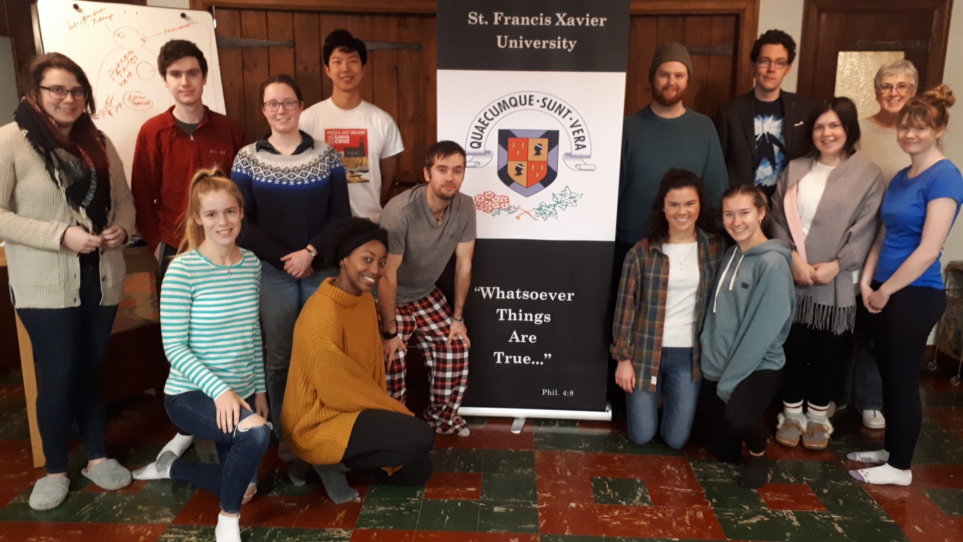 A group of people standing and kneeling with a university banner