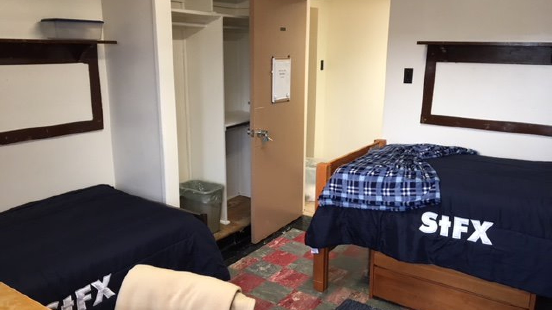 Double room in MacKinnon Hall with two beds, a closet, and a desk