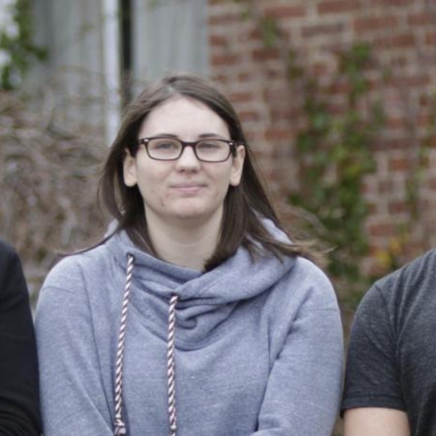 Five people posing for a photo in front of university building