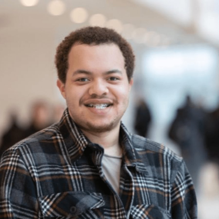 Headshot of a public policy degree student indoors with people walking in the background.