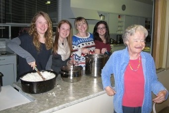 5 people standing around a kitchen counter smiling