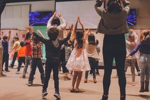 Kids dancing with hands above their heads