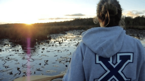 Student wearing a StFX sweater in a canoe on the lake