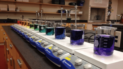 A row of beakers filled with colourful liquid on scales in the chemistry lab
