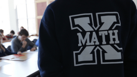 Close-up of student wearing a StFX Math sweater with students working in the background