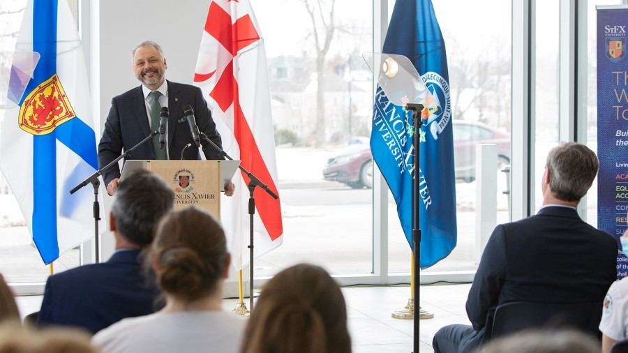 Dr. Andy Hakin standing at a podium with people watching