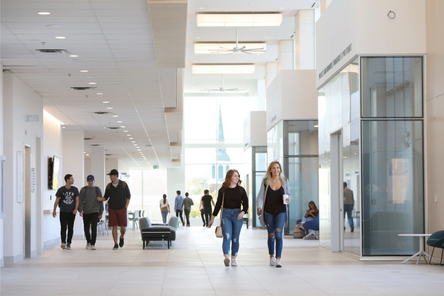 Students walking down a large, naturally lit corridor with light coloured walls