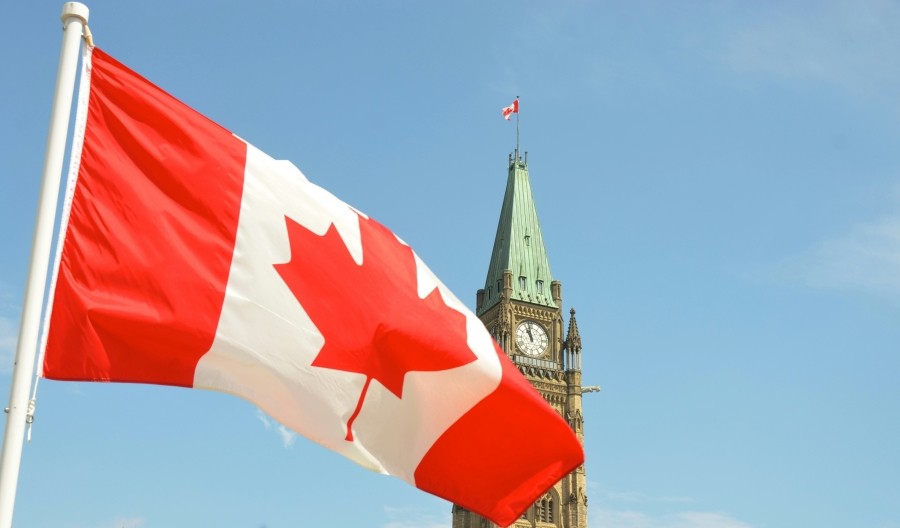 Canadian flag with the Peace Tower behind it.