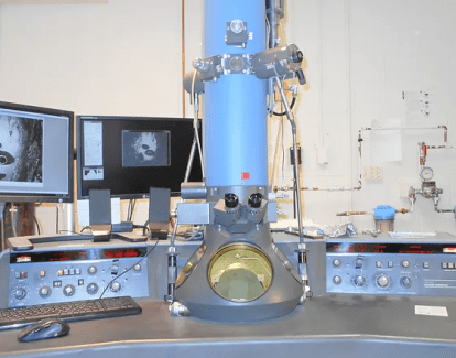 Image of a microscope on a table with equipment and screens